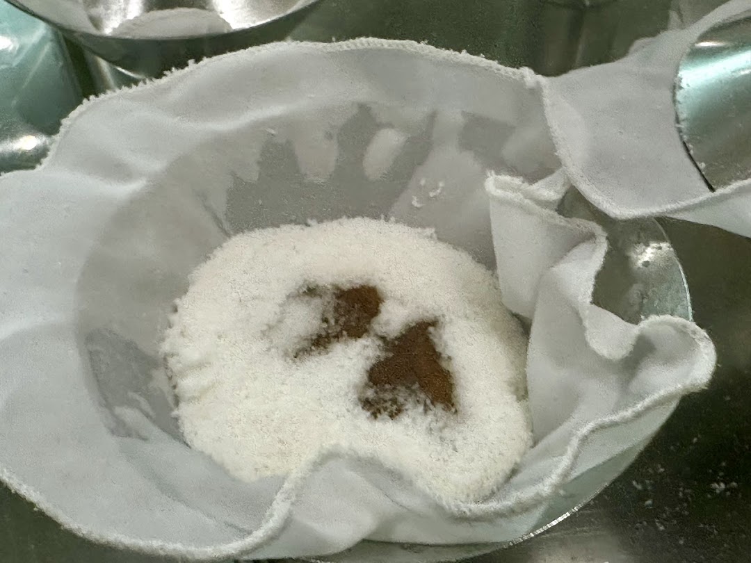 Close-up of putu piring ingredients, showing rice flour and gula melaka in a cloth mold.
