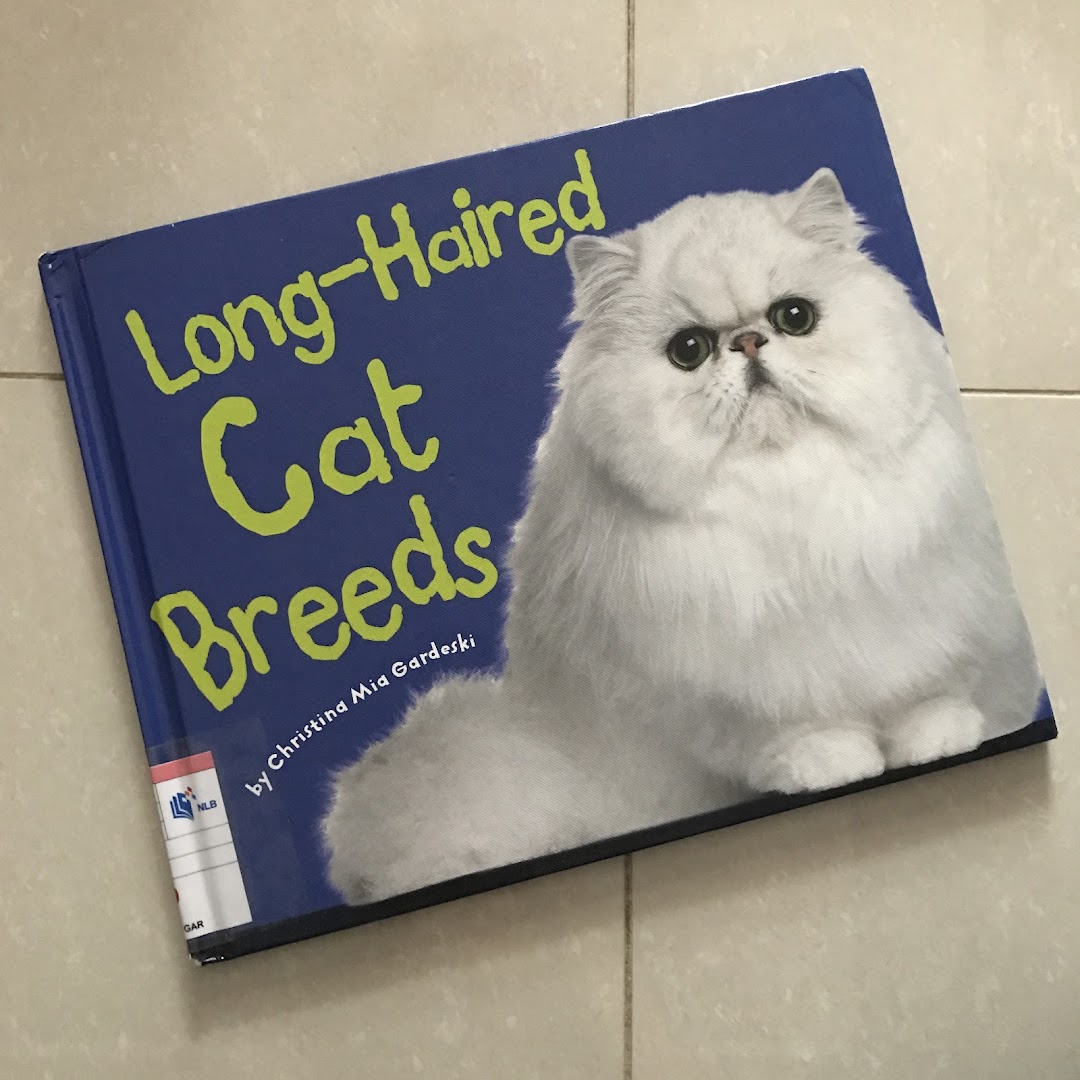 A book titled 'Long-Haired Cat Breeds' featuring a fluffy white cat on a blue cover.