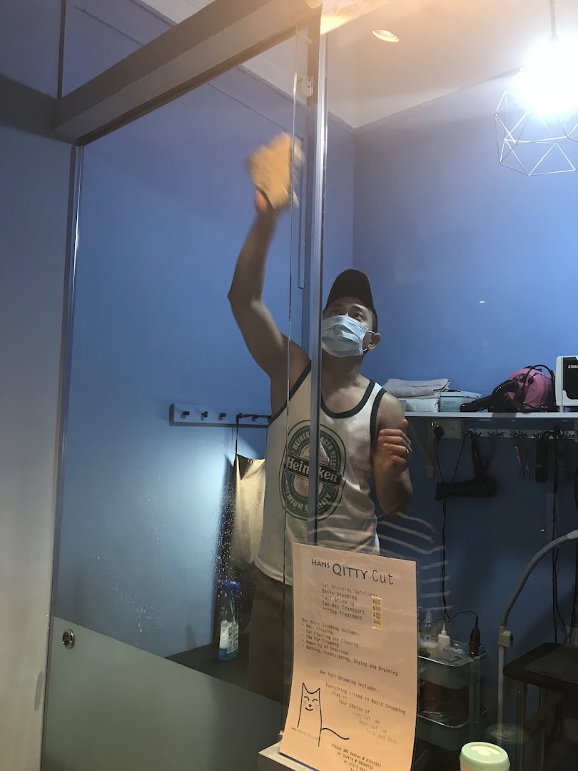 A price list for cat grooming services at Hans Qitty Cut, with a staff member cleaning.