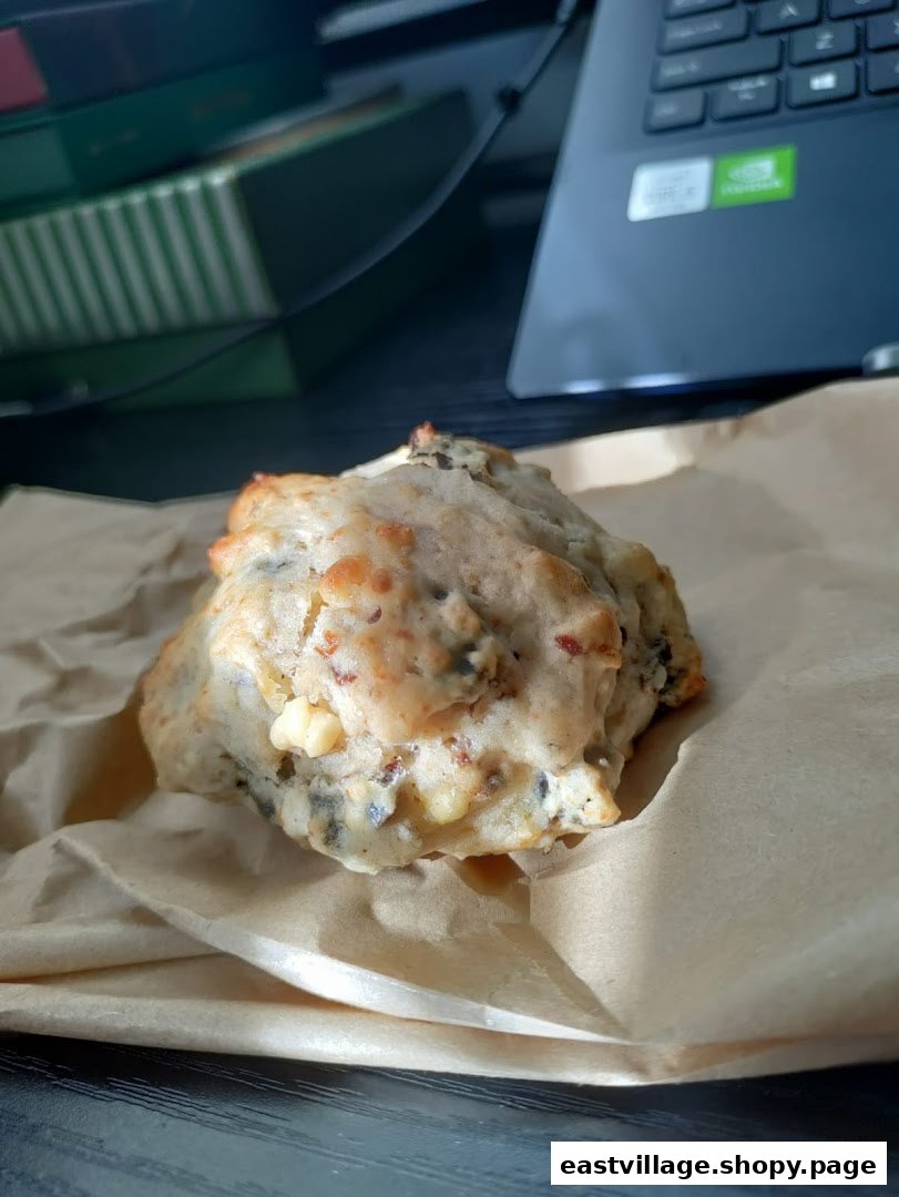A freshly baked, savory bun or scone from HappiBuns, wrapped in brown paper.