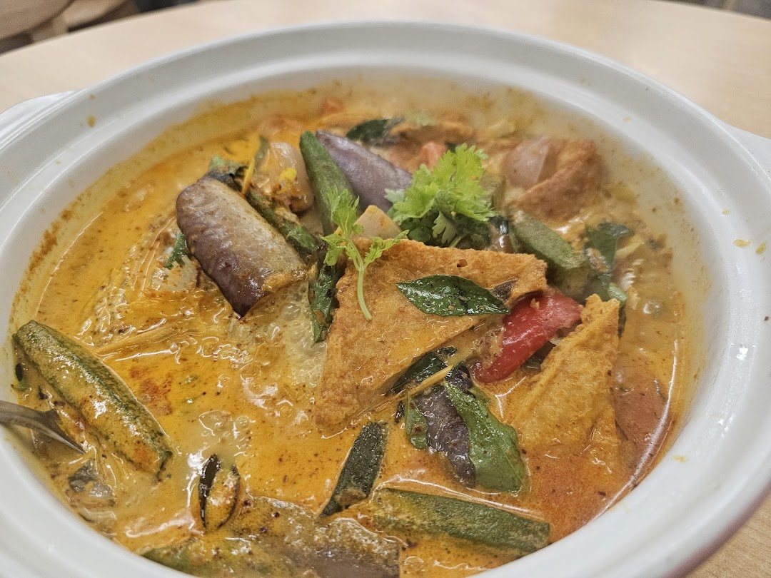 A vibrant bowl of rich curry with assorted vegetables and tofu puffs.