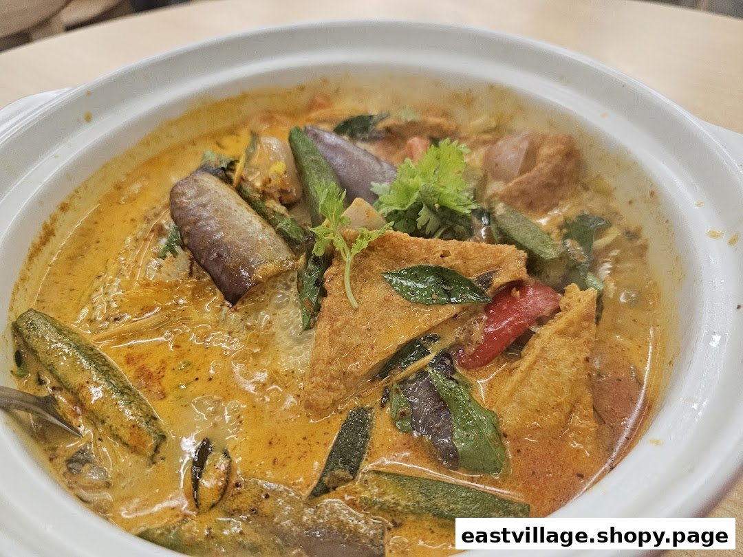A vibrant bowl of rich curry with assorted vegetables and tofu puffs.