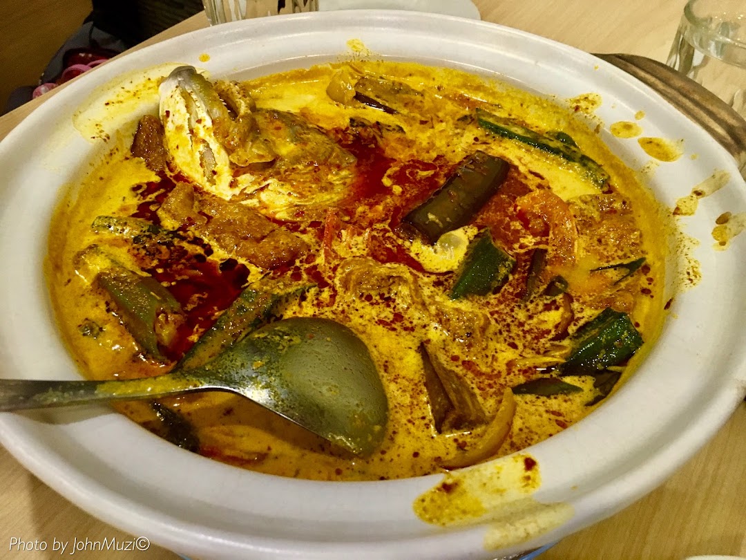 A vibrant claypot fish head curry with vegetables and a rich, spicy broth.
