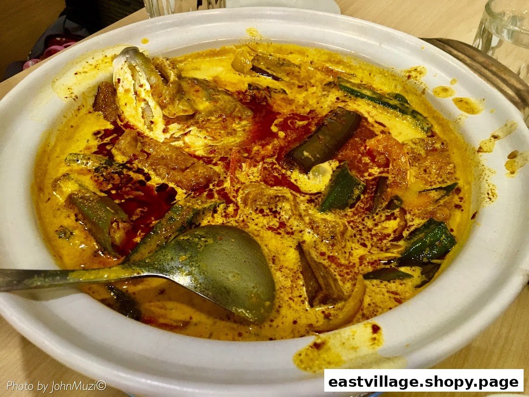 A vibrant claypot fish head curry with vegetables and a rich, spicy broth.