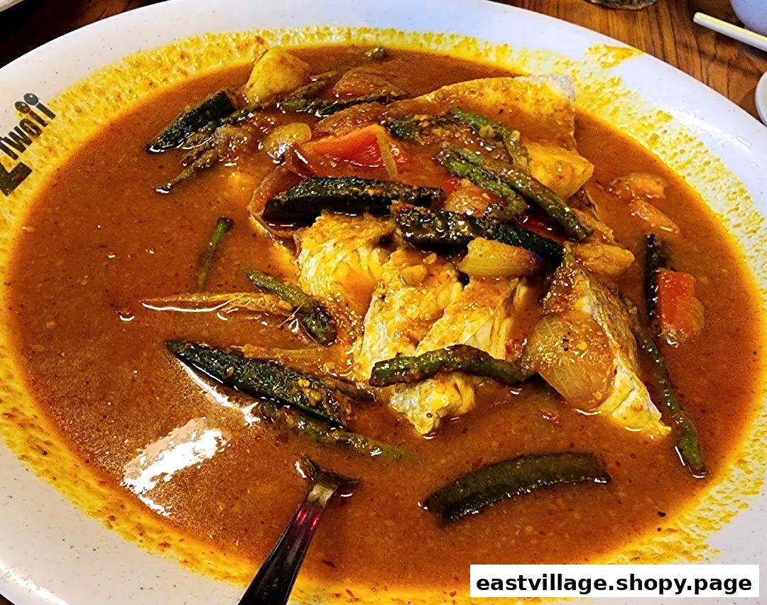 A vibrant close-up of a large plate of fish curry with vegetables in a rich, spicy sauce.