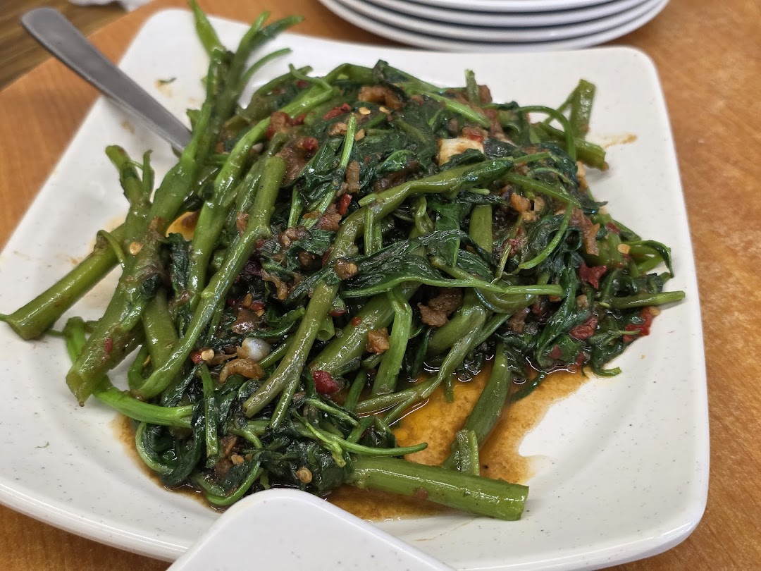 A close-up of a plate of stir-fried kangkong with chili and garlic, served on a white rectangular dish.
