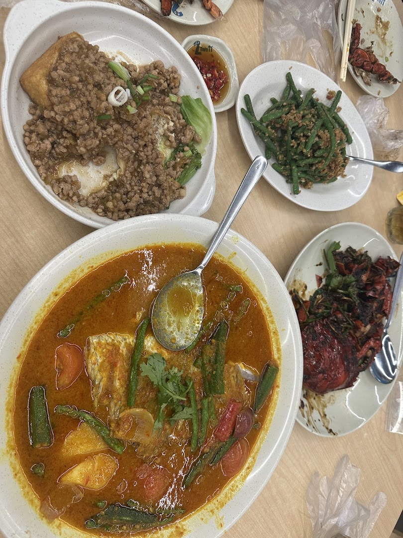A table laden with various delicious Asian dishes, including curry fish head, minced meat tofu, and stir-fried beans.