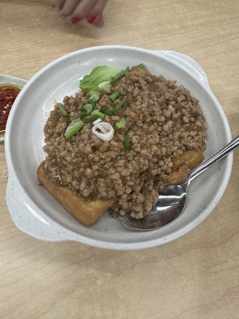 A close-up of a dish featuring fried tofu topped with minced meat and spring onions.