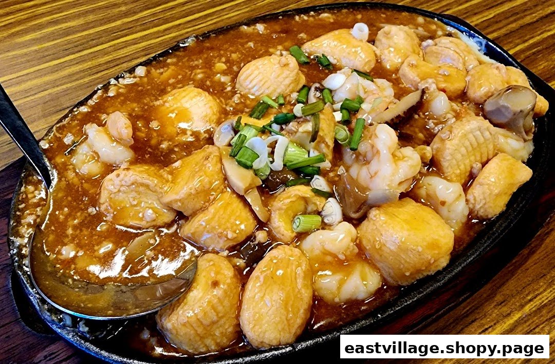A sizzling hotplate dish featuring golden tofu, succulent prawns, squid, and mushrooms in a rich savory sauce.