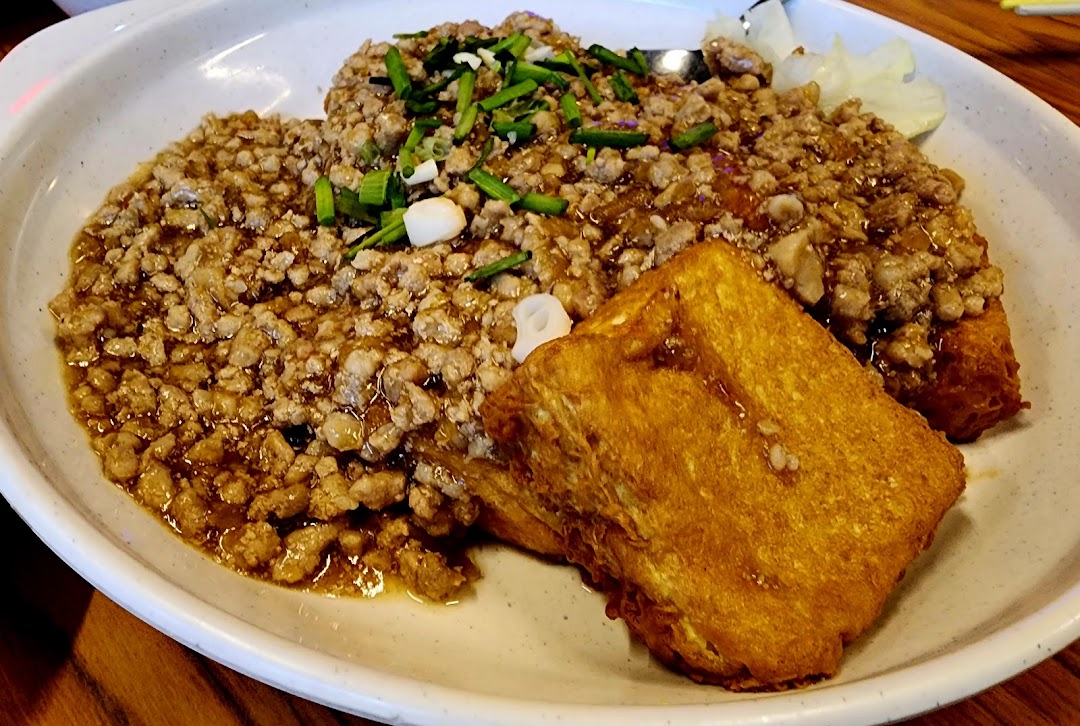 Close-up of minced meat sauce with spring onions and golden fried tofu.