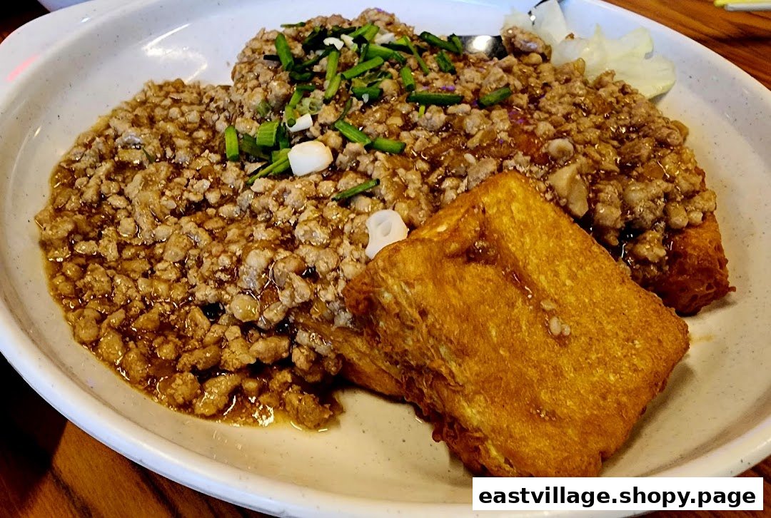 Close-up of minced meat sauce with spring onions and golden fried tofu.