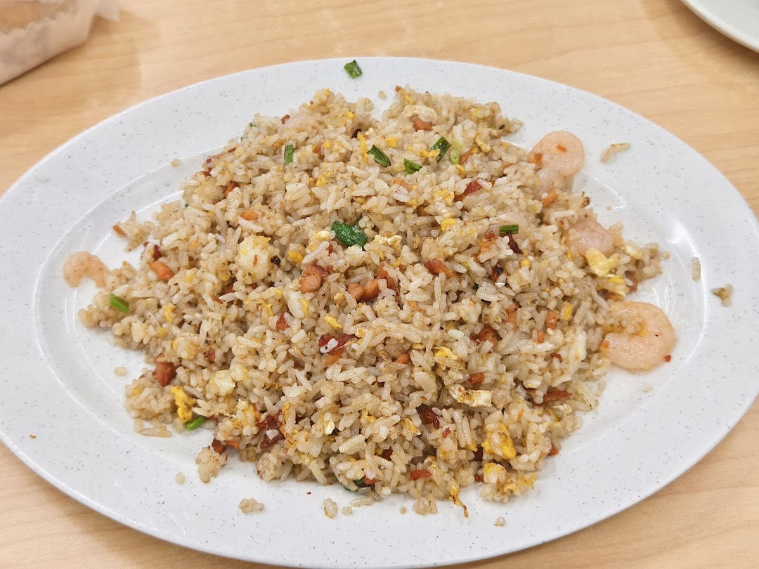 A close-up of a plate of Hong Kong-style fried rice with shrimp, egg, and char siu.