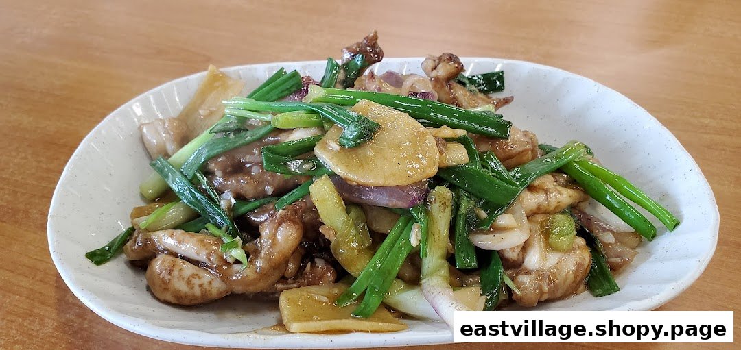 A close-up of a delicious stir-fried dish with chicken, spring onions, and other vegetables.