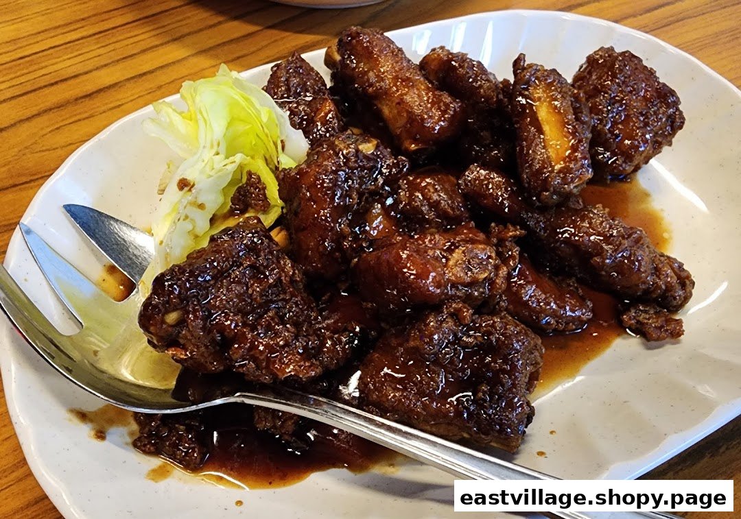 A plate of dark glazed ribs or chicken pieces with a side of fresh lettuce and a serving fork.