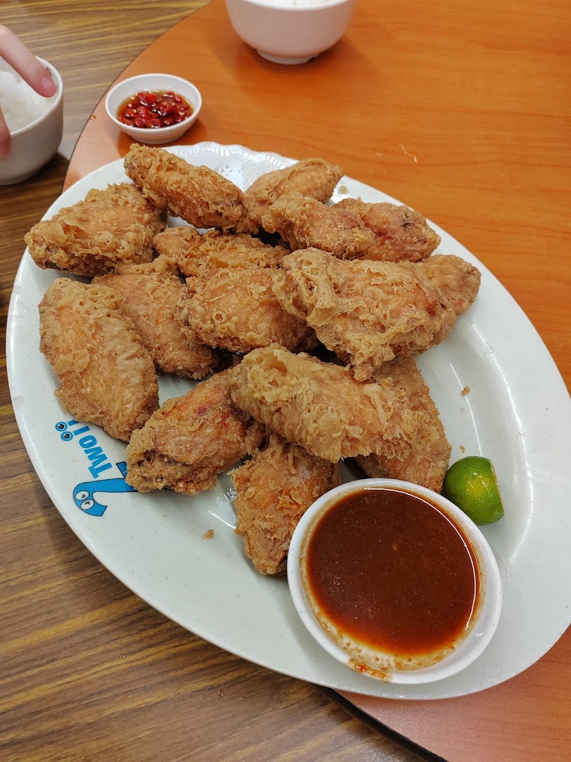 A large plate of crispy fried chicken wings with a side of dipping sauce and lime.