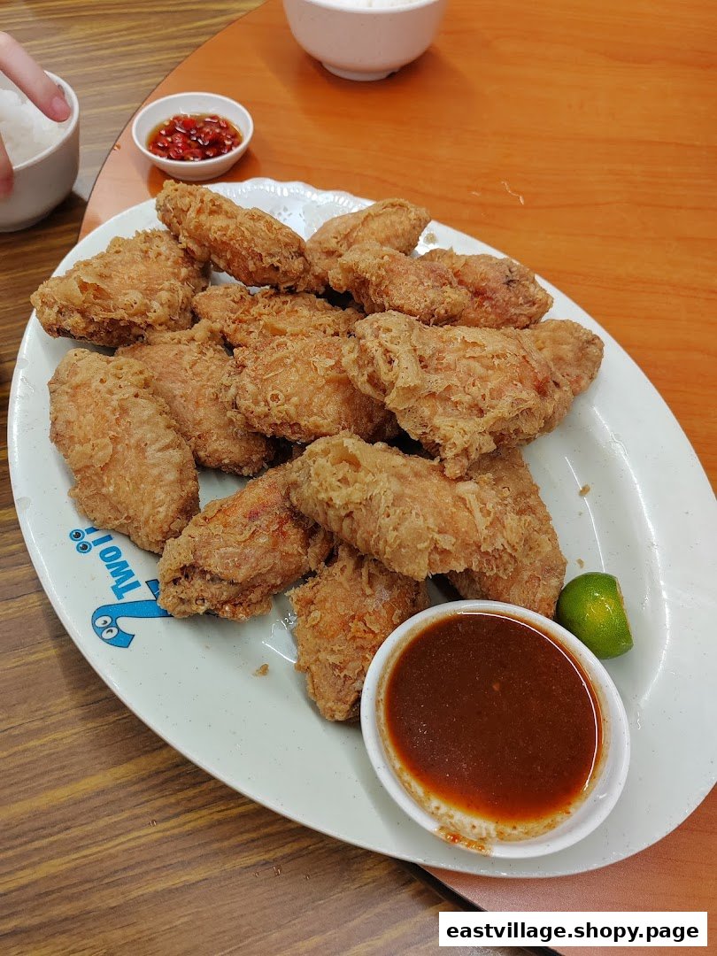 A large plate of crispy fried chicken wings with a side of dipping sauce and lime.