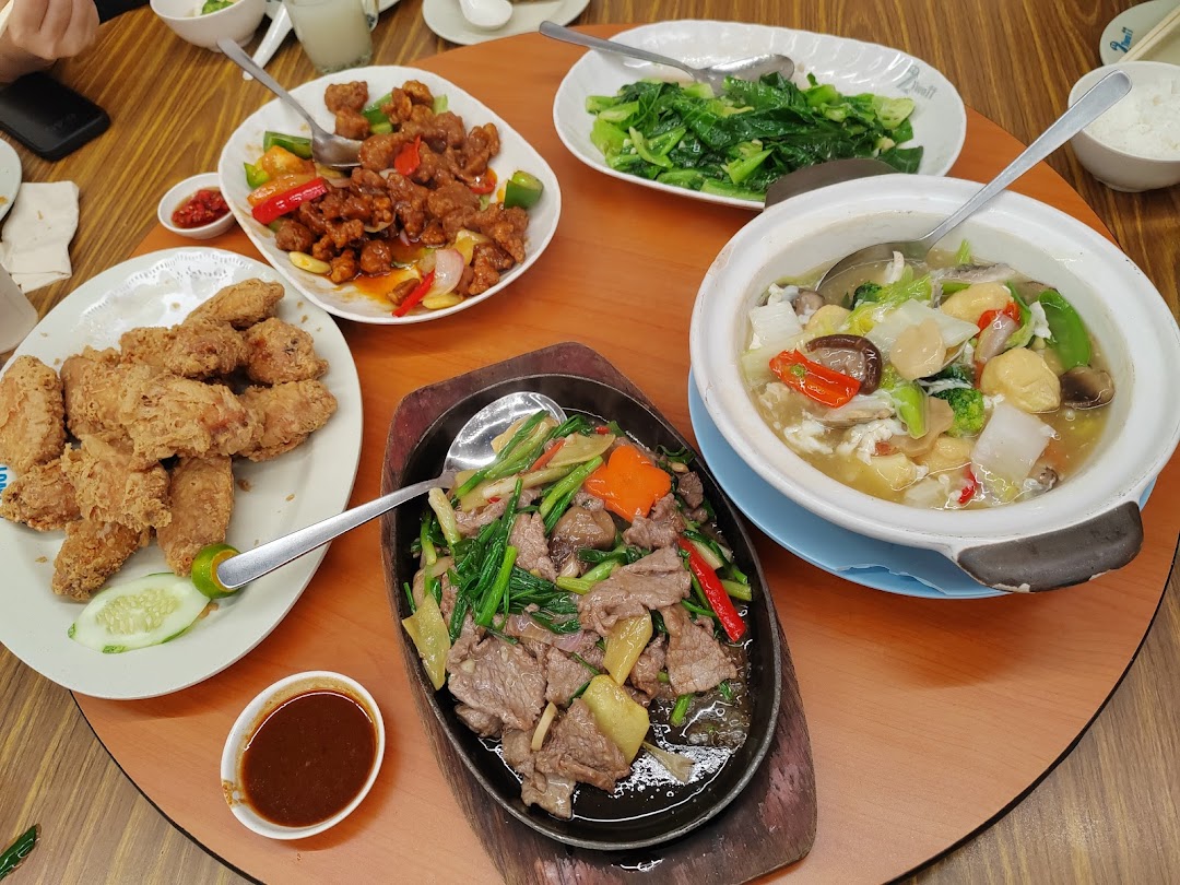 A table laden with various delicious Chinese dishes, including fried chicken, sweet and sour pork, and stir-fried beef.