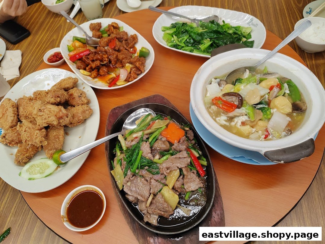 A table laden with various delicious Chinese dishes, including fried chicken, sweet and sour pork, and stir-fried beef.