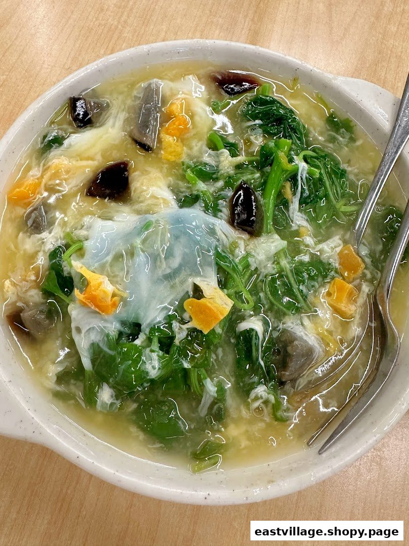A close-up of a hearty bowl of Chinese spinach soup with three types of eggs.