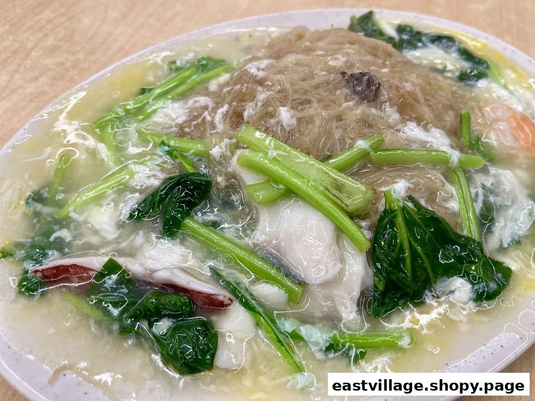 A close-up of a plate of seafood noodles with gravy, vegetables, and egg.