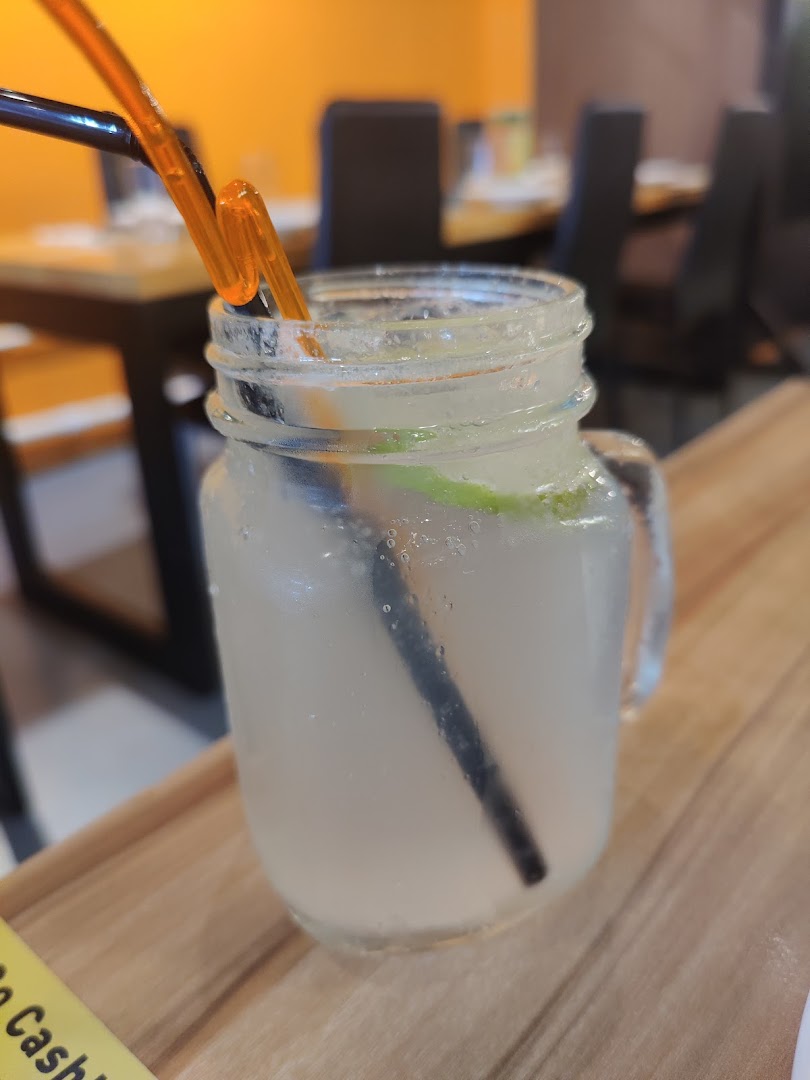 A refreshing drink in a mason jar with a straw, served on a wooden table inside the restaurant.