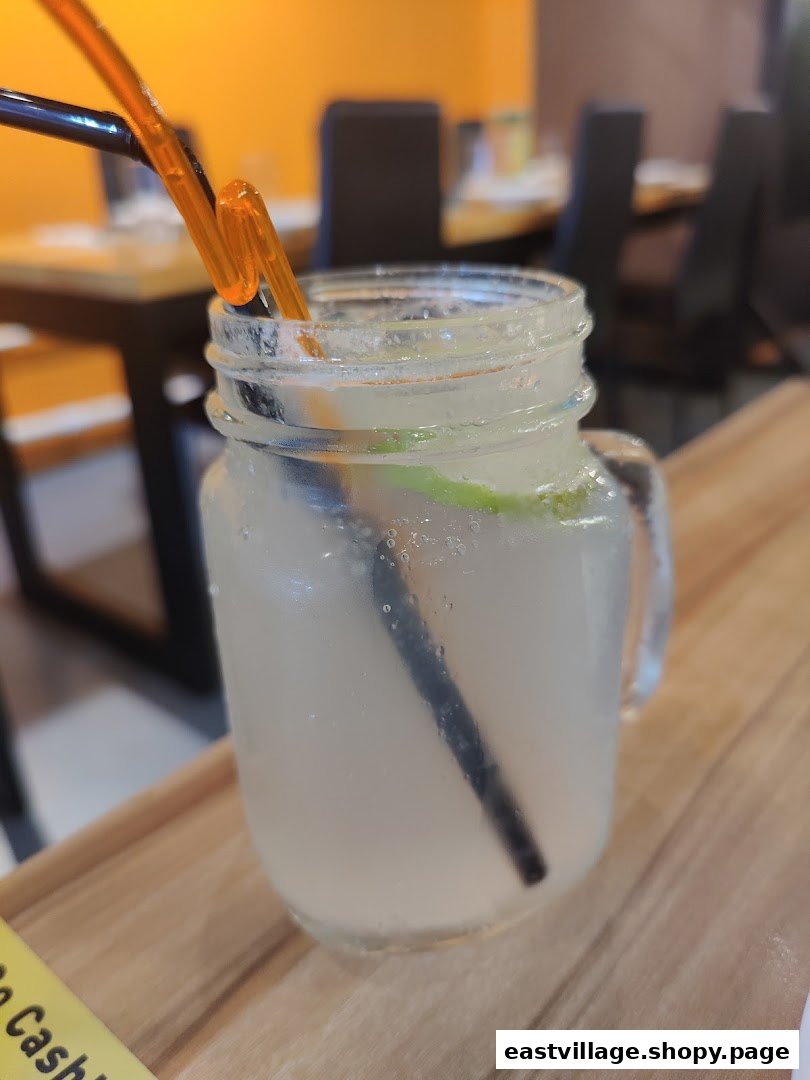 A refreshing drink in a mason jar with a straw, served on a wooden table inside the restaurant.