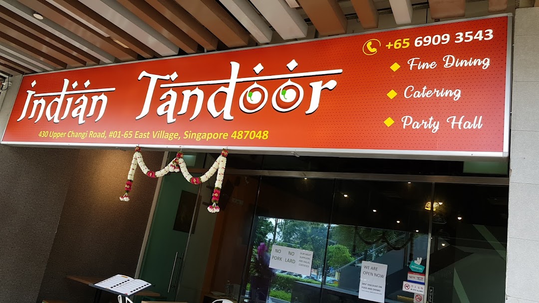 The image displays the vibrant red signboard and entrance of Indian Tandoor Restaurant, featuring contact and service details.