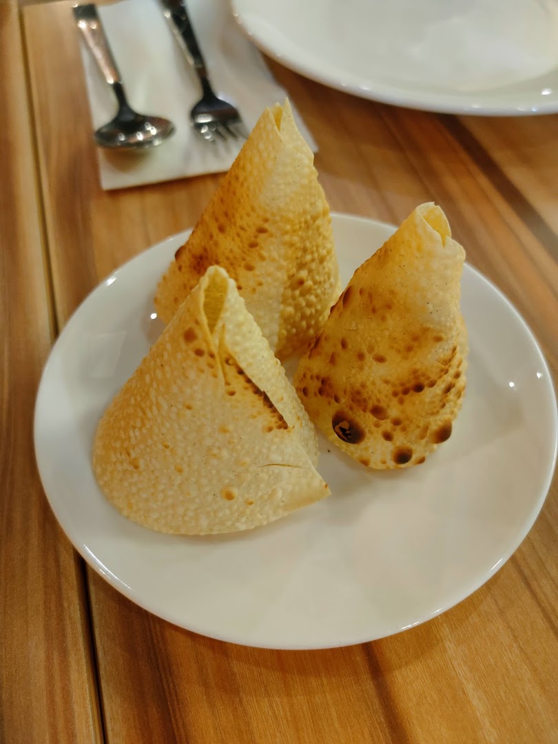 Three golden-brown, crispy papadums are served on a white plate, ready to be enjoyed.
