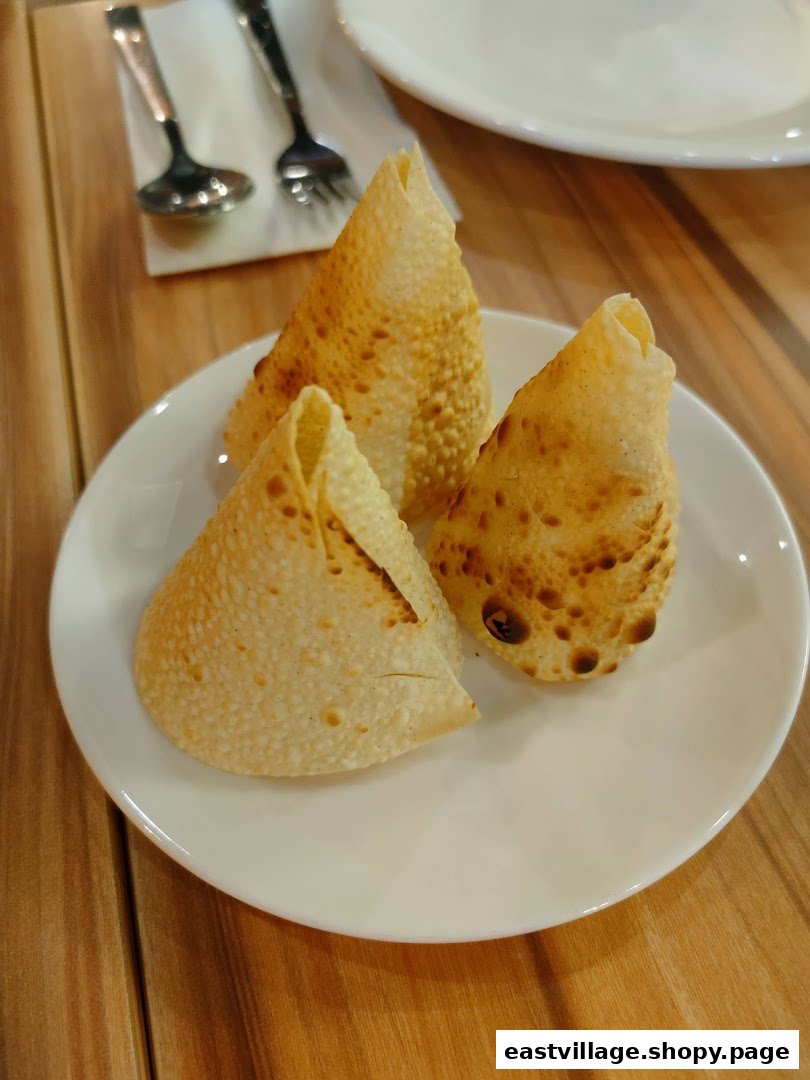 Three golden-brown, crispy papadums are served on a white plate, ready to be enjoyed.
