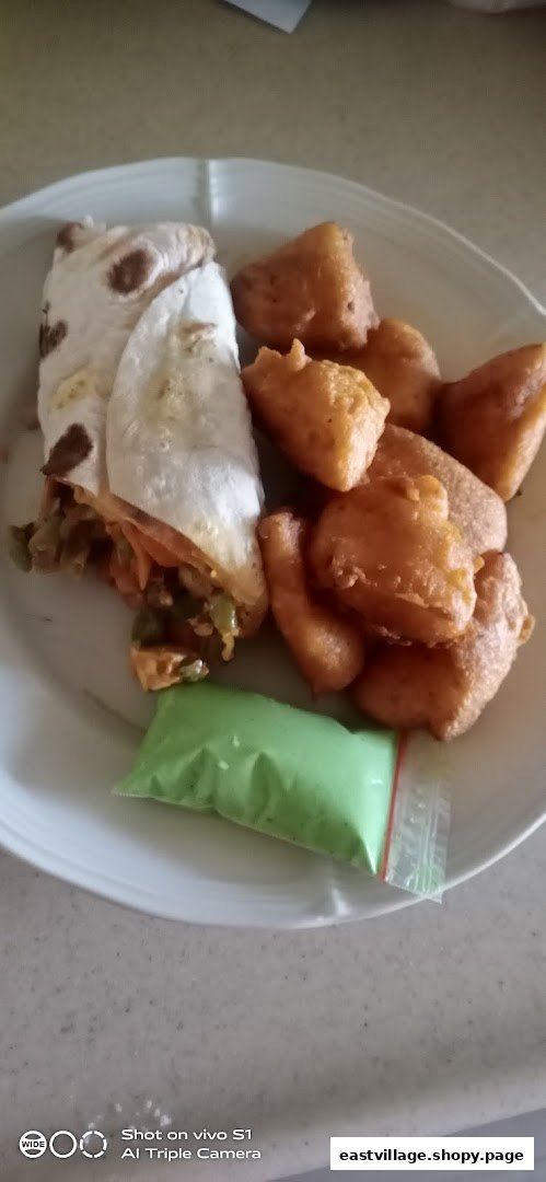 A plate featuring a savory wrap, golden fried snacks, and a vibrant green dipping sauce.