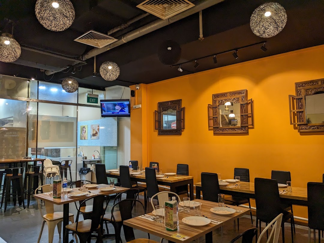 A vibrant interior of an Indian restaurant featuring orange walls, wooden tables, and decorative lighting.