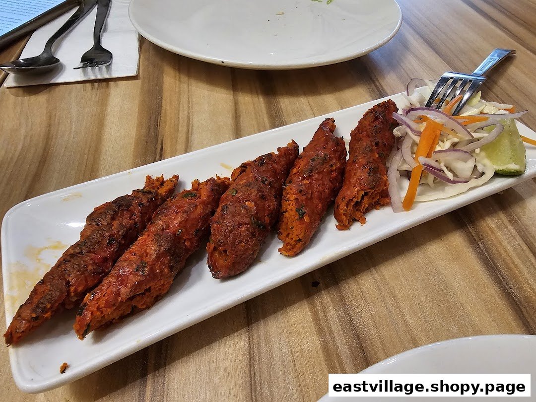 A plate of vibrant red seekh kebabs with a side of fresh salad and lime.