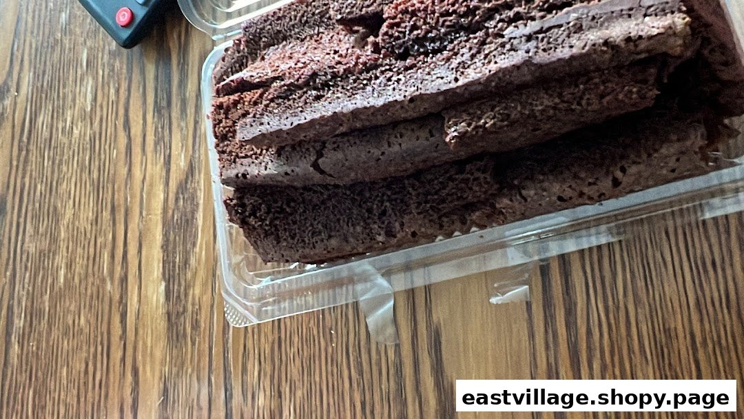 Slices of chocolate cake or brownie in a clear plastic container on a wooden surface.