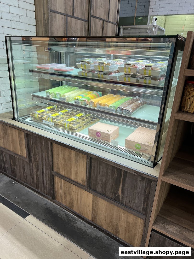A refrigerated display case showcasing a variety of fresh pastries, cakes, and baked goods at J C Bakery.