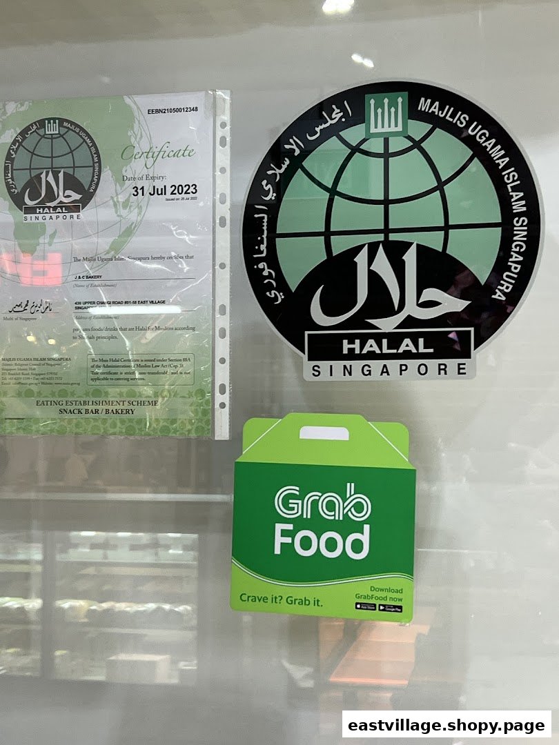 Halal certifications and a GrabFood sticker displayed on the window of J C Bakery.