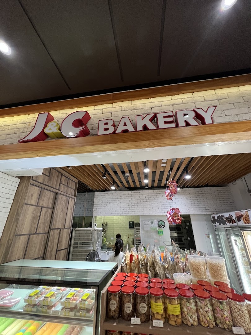 Interior view of J C Bakery showcasing various baked goods, snacks, and the shop's branding.