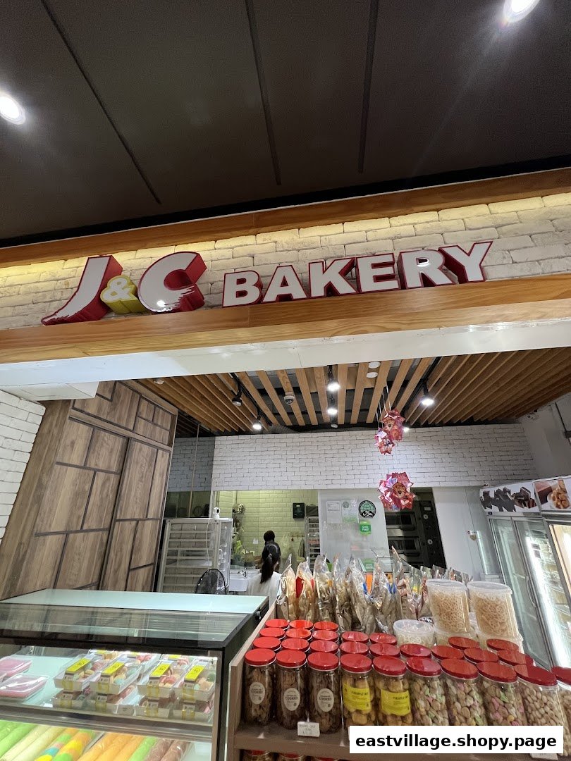 Interior view of J C Bakery showcasing various baked goods, snacks, and the shop's branding.