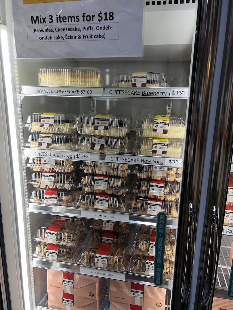 A refrigerated display case showcasing various cakes, cheesecakes, and eclairs with a promotional offer.