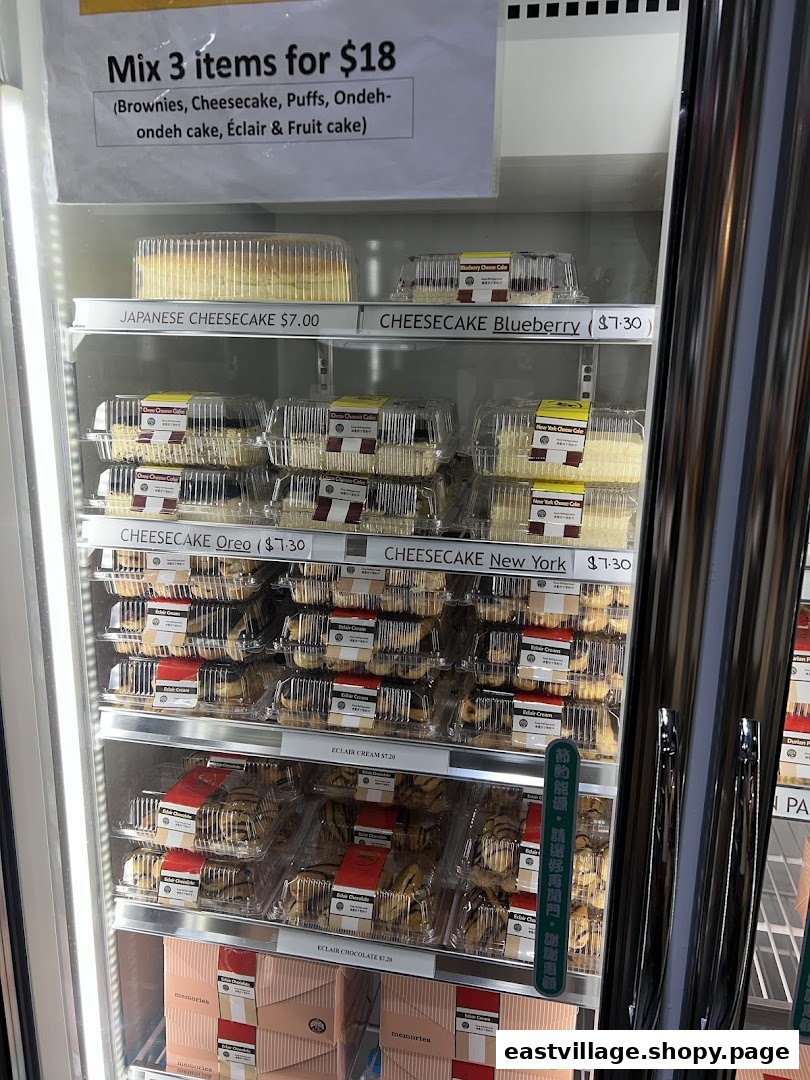 A refrigerated display case showcasing various cakes, cheesecakes, and eclairs with a promotional offer.