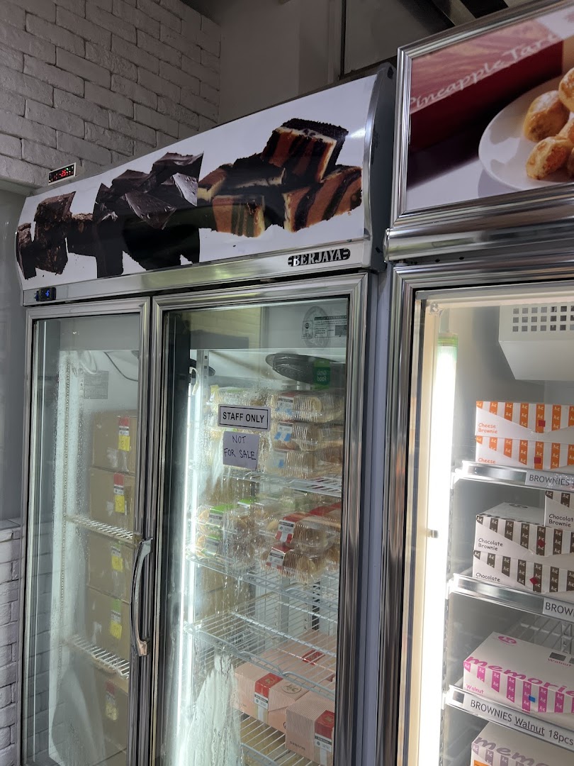 Display refrigerators at J C Bakery showcasing various baked goods like brownies and cakes, with a 'Staff Only' section.