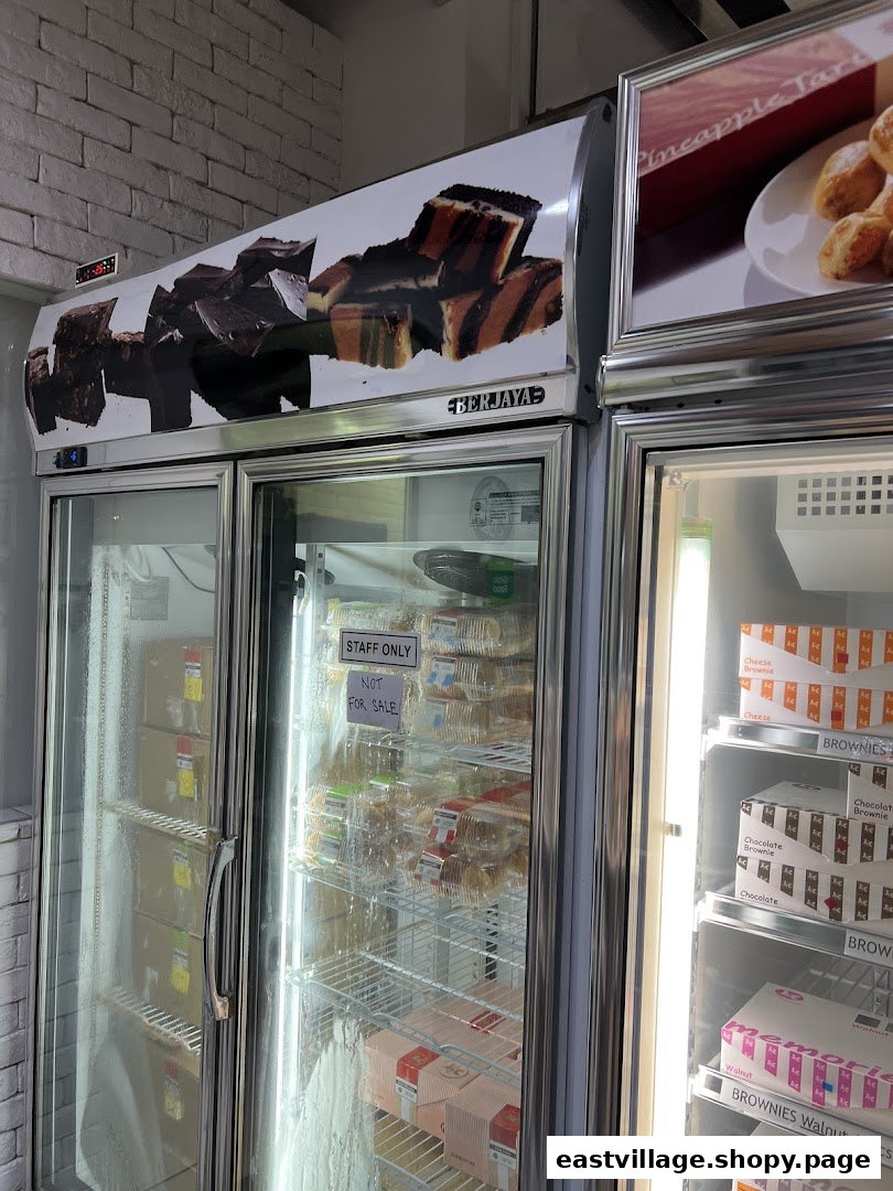Display refrigerators at J C Bakery showcasing various baked goods like brownies and cakes, with a 'Staff Only' section.