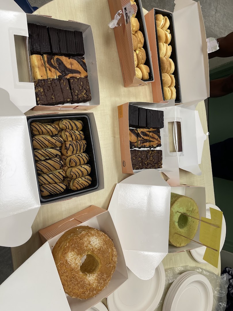 An assortment of delicious baked goods, including brownies, cream puffs, and cakes, in open takeaway boxes.