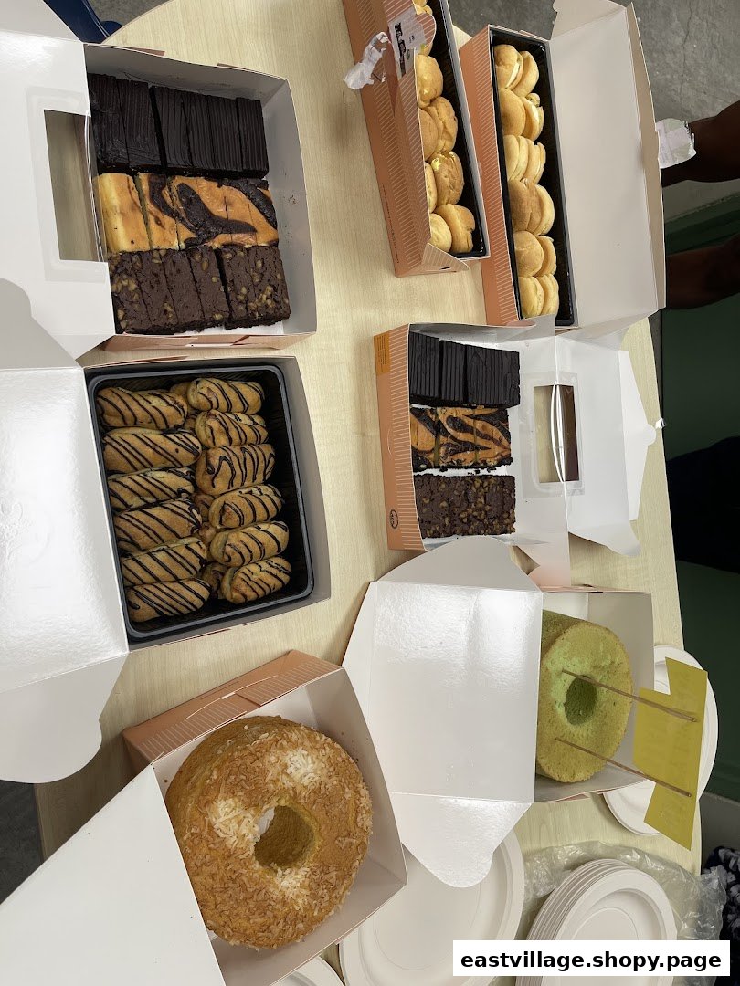 An assortment of delicious baked goods, including brownies, cream puffs, and cakes, in open takeaway boxes.
