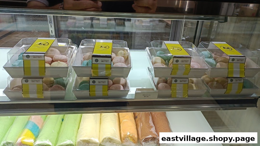 A display case filled with packaged mochi-like desserts and rolled cakes at J C Bakery.
