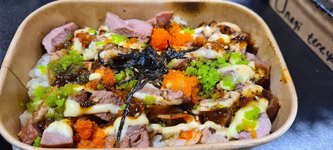 A vibrant rice bowl featuring sliced meats, colorful roe, seaweed, and creamy sauce in a paper container.