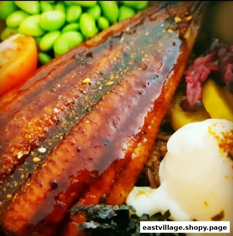 A close-up of a delicious unagi dish with edamame, tomato, and a creamy sauce.