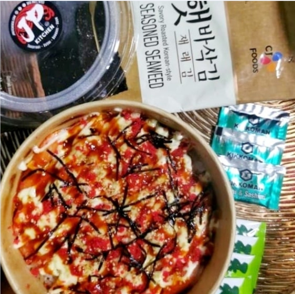 A close-up of a delicious-looking food bowl with toppings, alongside seasoned seaweed and soy sauce packets.