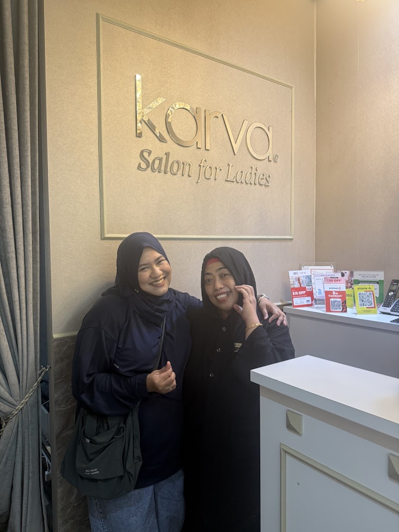 Two smiling women stand in front of the KARVA Salon for Ladies sign, showcasing the welcoming interior.