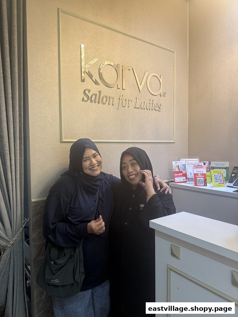 Two smiling women stand in front of the KARVA Salon for Ladies sign, showcasing the welcoming interior.