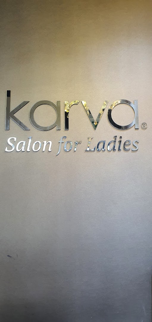 Close-up of the elegant 'KARVA Salon for Ladies' sign on a wall.